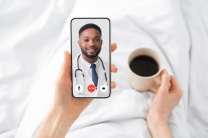Doctor on phone screen of woman in bed