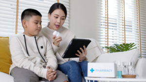 Asian woman and son on iPad talking to doctor