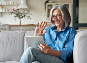 Older woman on video call waving to tablet