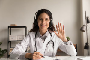 Smiling female doctor waving to screen