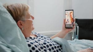 Elderly woman in hospital bed on video call with younger woman