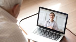 elderly man on video call with female doctor on laptop