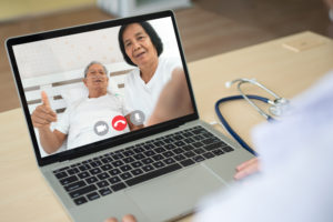 Elderly asian couple on laptop with doctor