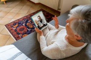 Elderly woman waving to doctor on video call