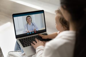Woman and young child looking at a doctor on a laptop screen